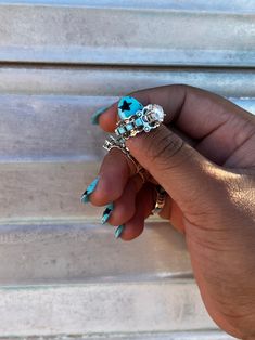 a woman's hand with blue and white nail polish holding a ring