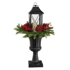 a candle is sitting on top of a black vase with red berries and greenery