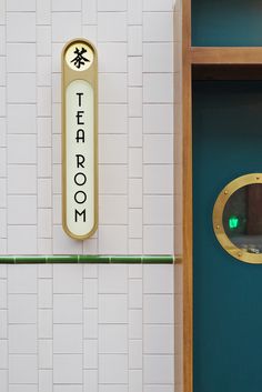 there is a sign that says tea room on the wall next to a green door