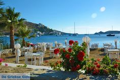 tables and chairs set up on the beach with boats in the water behind them,