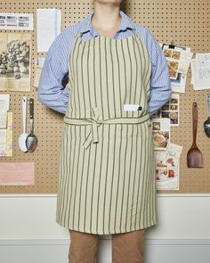 a man wearing an apron standing in front of a bulletin board