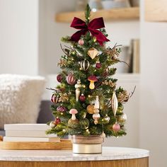 a small christmas tree with ornaments and bows on it's top, sitting on a table