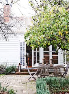 an outdoor table and chairs in front of a white house