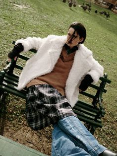 a man sitting on top of a green park bench