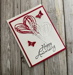 a happy anniversary card with red and white paper butterflies on the front, sitting on a wooden surface