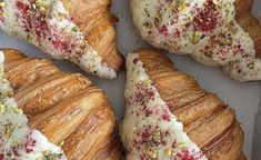 four croissants with white frosting and sprinkles on them