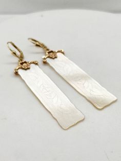 Chinese gaming counters became incredibly popular in the late 1800's and were often adorned with hand carved family crests or initials.  These beautiful counters are made from Mother of Pearl and are etched with delicate floral patterns and set on custom 14k yellow gold bails.  Lever back closures gives additional security as well as nice movement with these delicate dangle earrings! Elegant Carved Earrings For Formal Occasions, Elegant Carved Drop Earrings, Formal Etched Bronze Jewelry, Elegant Brass Ceremonial Earrings, Classic Ceremonial Brass Jewelry, Carved Sterling Silver Heirloom Jewelry, Elegant Sterling Silver Ceremonial Earrings, Elegant Ceremonial Sterling Silver Earrings, Classic Intaglio Earrings As A Gift