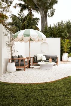 an outdoor living area with couches, tables and umbrella