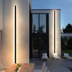 an exterior view of a modern house at night with lights on the walls and doors