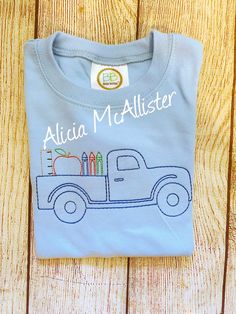 Baby blue short sleeve tee school truck embroidery design.  My name appears on my photos only as a watermark to protect my work, it will not be included in yoir item.  Tees available in sizes 12 mon to 8 (no size 7)  Other appliqué designs or monogramming available upon request. Cute T-shirt With Machine Embroidery And Short Sleeves, Cute Machine Embroidered Short Sleeve T-shirt, Cute Blue T-shirt For End Of School Year, Blue T-shirt For School, Blue School Spirit T-shirt For End Of School Year, Blue Short Sleeve T-shirt With Embroidered Graphics, Blue Embroidered Graphics Short Sleeve T-shirt, Blue Embroidered Graphics T-shirt With Short Sleeves, Pre-shrunk Blue T-shirt For School