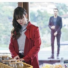 a woman standing in front of a table with food on it and another man behind her