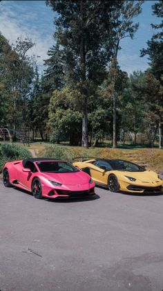 two pink and yellow sports cars parked next to each other in a parking lot surrounded by trees