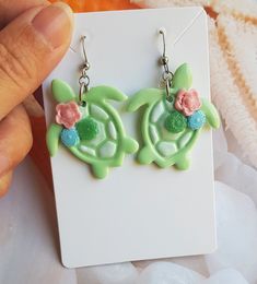 These cute Sea Turtle Earrings are handmade from polymer clay, resulting in a unique and eye-catching accessory. The earrings feature a beautifully painted shell design with delicate floral and succulent decorations in a mixture of pastel colours. Measuring approximately 3 cm in length, these earrings are the perfect size to make a statement. Despite their detailed design, they are remarkably lightweight, ensuring comfortable wear throughout the day. To add a touch of elegance and durability, ea Themed Polymer Clay Jewelry For Gifts, Playful Personalized Polymer Clay Jewelry, Whimsical Polymer Clay Earrings For Gift, Whimsical Polymer Clay Earrings As Gift, Turquoise Resin Earrings For Gift, Cute Multicolor Polymer Clay Jewelry, Playful Handmade Polymer Clay Jewelry, Cute Multicolor Polymer Clay Earrings, Cute Handmade Green Jewelry