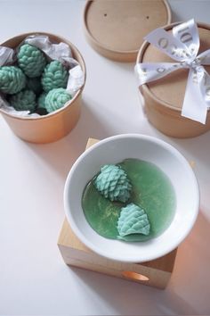 two bowls filled with green food on top of a white table next to wooden boxes