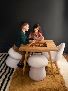 two children are sitting at a table playing with a board game on top of it