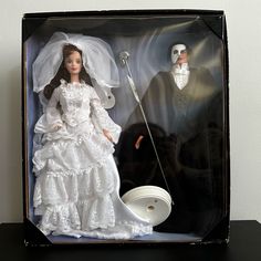 a bride and groom doll in a black box with white dress, veil, and cane