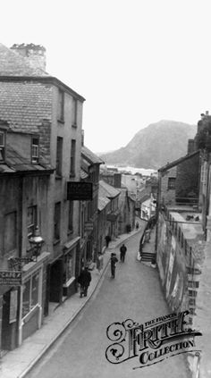 an old black and white photo of people walking down the street in front of buildings