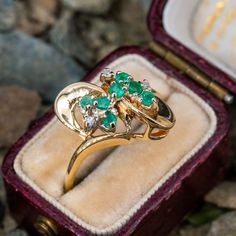 This estate emerald ring features seven round cut emeralds with single cut diamond accents in a swirl of gold. The ring is crafted in 14k yellow gold and is currently a size 8. Estate Rings Vintage, Vintage Emerald Ring, Estate Jewelry Rings, Faberge Jewelry, Emerald Ring Vintage, Estate Rings, Emerald Diamond Ring, Fantasy Jewelry, October Birth Stone