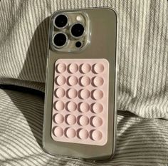 an iphone case with circles on it sitting on top of a bed next to a pillow