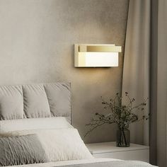 a white bed sitting next to a window with a lamp on it's side