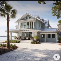 a large white house sitting on top of a sandy beach next to the ocean and palm trees