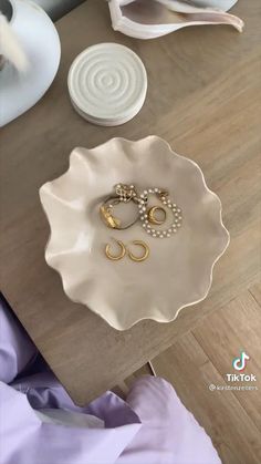 two wedding rings are sitting on a white plate next to other jewelry items and plates