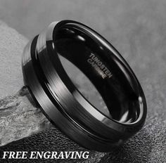 a black wedding ring sitting on top of a rock