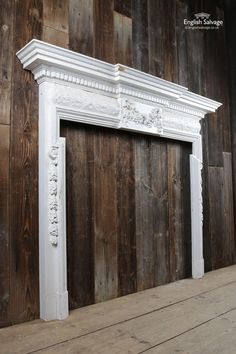 an old white fireplace with wood paneling in the background