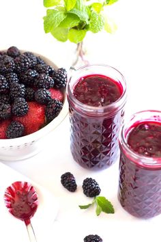 berries and yogurt in jars with spoons next to them on a white surface