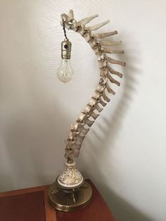 a lamp that is on top of a wooden table with bones attached to the light bulb