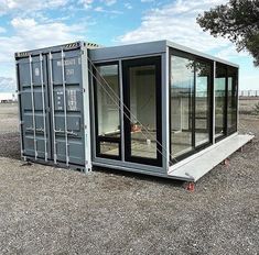 a shipping container sitting in the middle of a field with its doors open and windows closed