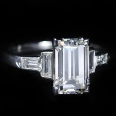 an emerald cut diamond ring with baguets on the sides and tapered shoulders