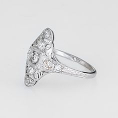 This is part of Chairish’s Fine Jewelry assortment.  Finely detailed vintage Art Deco era ring (circa 1920s to 1930s) crafted in 18k white gold.   Nine old mine cut diamonds total an estimated 0.60 carats (estimated at I-J colour and SI2-I1 clarity).   The ring features a lacy filigree design with an elongated mount, a hallmark of the Art Deco era. The mount has a slightly curved saddle for a comfortable fit on the finger. The ring has a low profile rising 4mm from the finger (0.15 inches).    T Vintage Diamond Cut Signet Ring For Wedding, Vintage White Gold Signet Ring, Vintage Wedding Signet Ring, Antique Diamond Ring With Accents For Vintage Events, 14k White Gold Signet Ring For Wedding, Vintage White Gold Diamond Cut Ring, Vintage Filigree Ring With Single Cut Diamonds, Vintage Signet Ring With Diamond Accents, Vintage Engraved Diamond Ring With Single-cut Diamonds