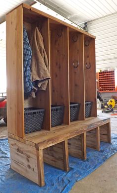 a wooden bench with baskets on top of it and clothes hanging from the back wall