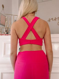 The Emma Sports Bra Top from Sassy Shortcake is hot pink and features overlay straps on back with a hook closure. This top has four way stretch, removable pads, and moisture wicking fabric. Model wearing size small. Matching leggings also available. Nylon Strappy Back Activewear For Workout, Nylon Activewear With Strappy Back For Workout, Pink Stretch Activewear For Light Exercise, Pink Nylon Sports Bra For Light Exercise, Pink High Stretch Sports Bra For Workout, Fitted Pink Activewear For Sports, Stretch Strappy Back Activewear For Yoga, Strappy Back Stretch Activewear For Yoga, Sleeveless Activewear With Crisscross Straps For Workout