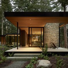 a modern house in the woods surrounded by rocks and trees with stairs leading up to it