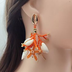 Brighten up your look with these Orange and White Coral Stud Earrings, expertly handcrafted from Japanese Delica beads. Each earring features detailed beaded coral branches and intricately beaded starfish in vibrant orange and crisp white tones. Enhanced with genuine seashells and 18K gold-filled accents, these earrings radiate both luxury and natural beauty. The 18K gold-filled stud closures, designed as delicate seashells, add a sophisticated finishing touch. Ideal for beach lovers and those w Beach Earrings With Dangling Beads, Bohemian Dangle Beaded Earrings For Vacation, Bohemian Beaded Earrings For Vacation, Bohemian Coral Jewelry For The Beach, Bohemian Coral Jewelry For Beach, Coral Bohemian Beach Jewelry, Handmade Beaded Earrings For Beach, Bohemian Beaded Dangling Earrings For Vacation, Bohemian Orange Beaded Earrings For Beach