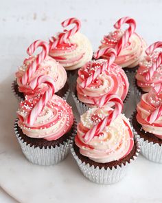 cupcakes with white frosting and candy canes on top are sitting on a plate