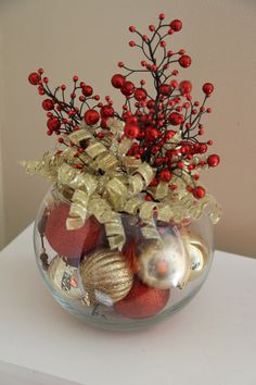 a glass bowl filled with ornaments on top of a white table next to a wall