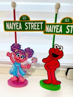 two sesame street signs are standing next to each other