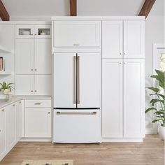 a white kitchen with wooden floors and cabinets