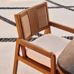 a close up of a wooden chair with a cushion on it and a table in the background