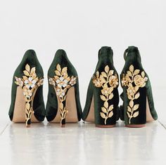 four pairs of green shoes with gold flowers and leaves on the heel, all lined up in a row