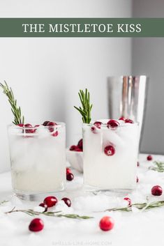 two glasses filled with ice, cranberries and rosemary sprigs on the table