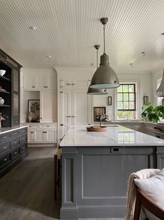 a large kitchen with an island in the middle and two pendant lights hanging from the ceiling