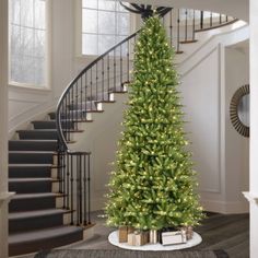 a christmas tree in the middle of a living room with stairs leading up to it