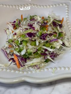 a white plate topped with coleslaw next to carrots and celery