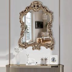 an ornate gold framed mirror hangs on the wall next to a console table and chair