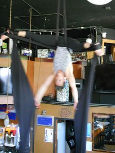 two people doing aerial acrobatic tricks in a room full of televisions