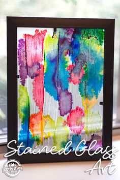 an art project with watercolor paint and black frame on a window sill in front of